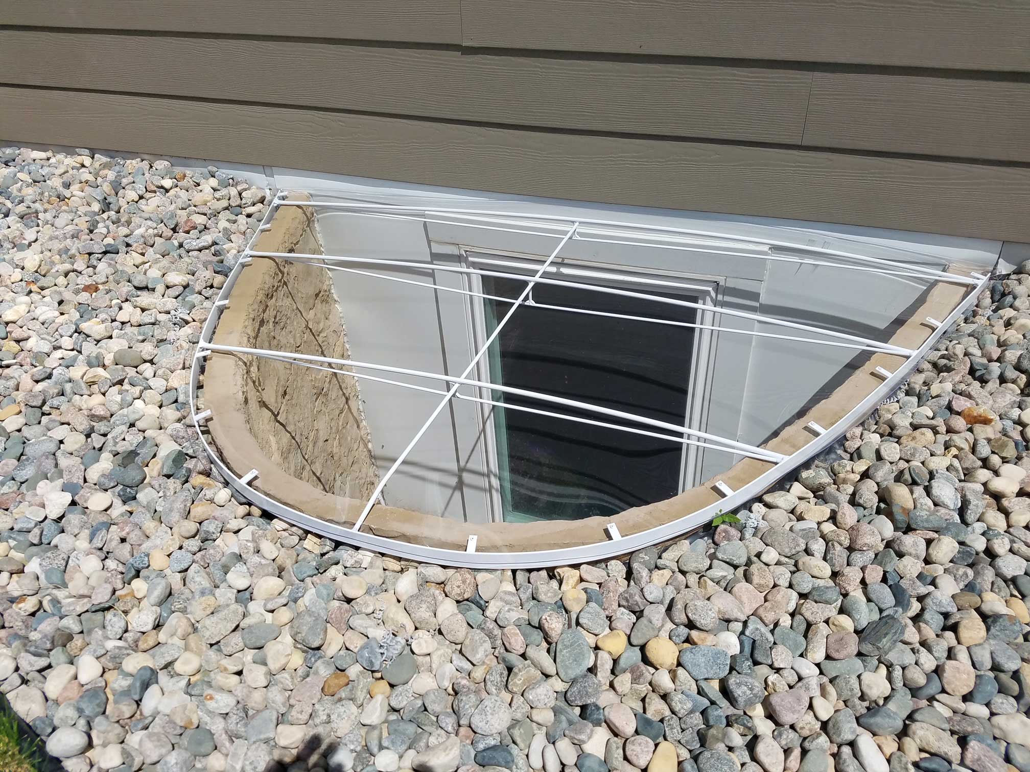 Basement window with protective cover and stones