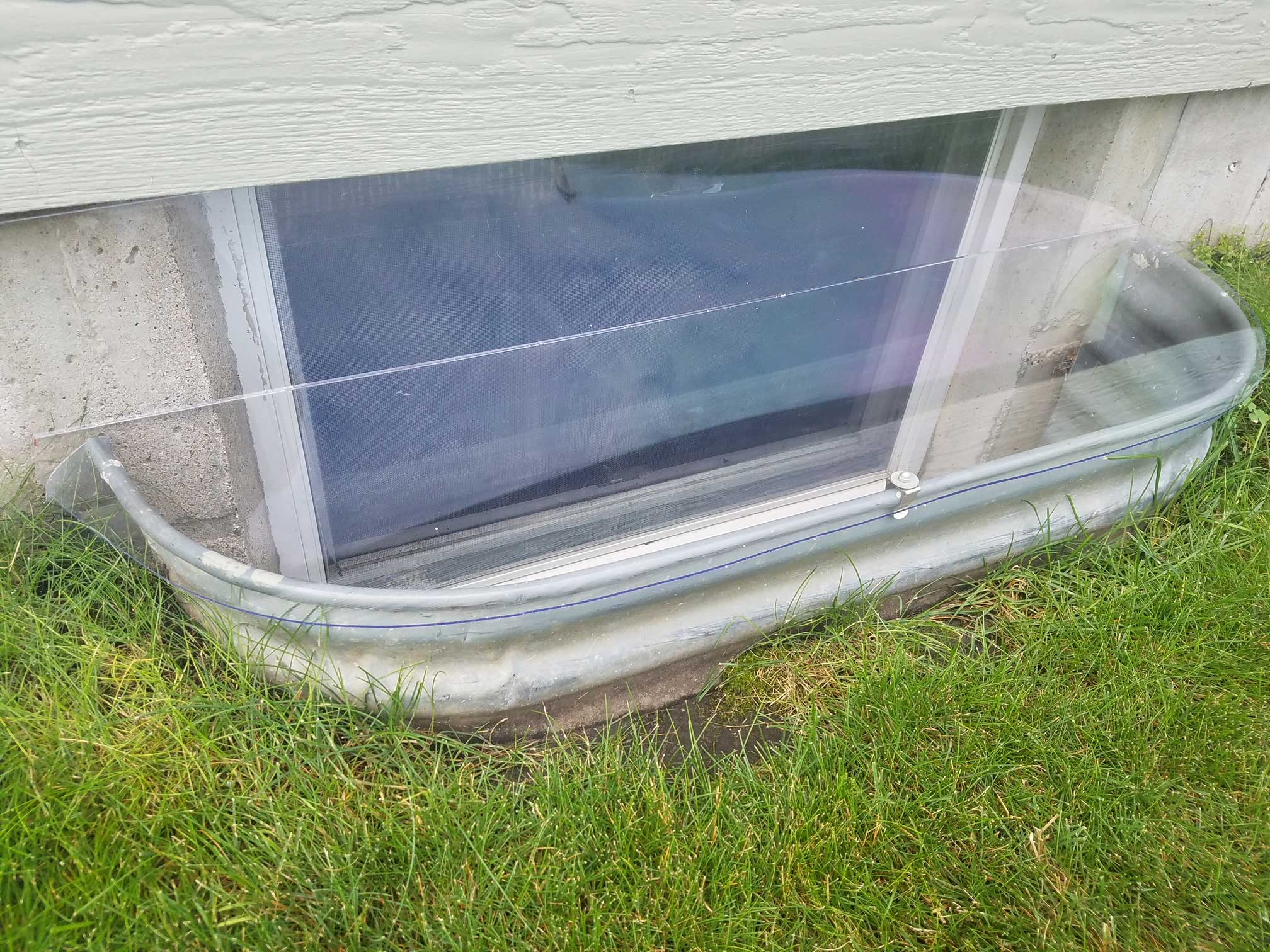 Metal basement window well with clear cover