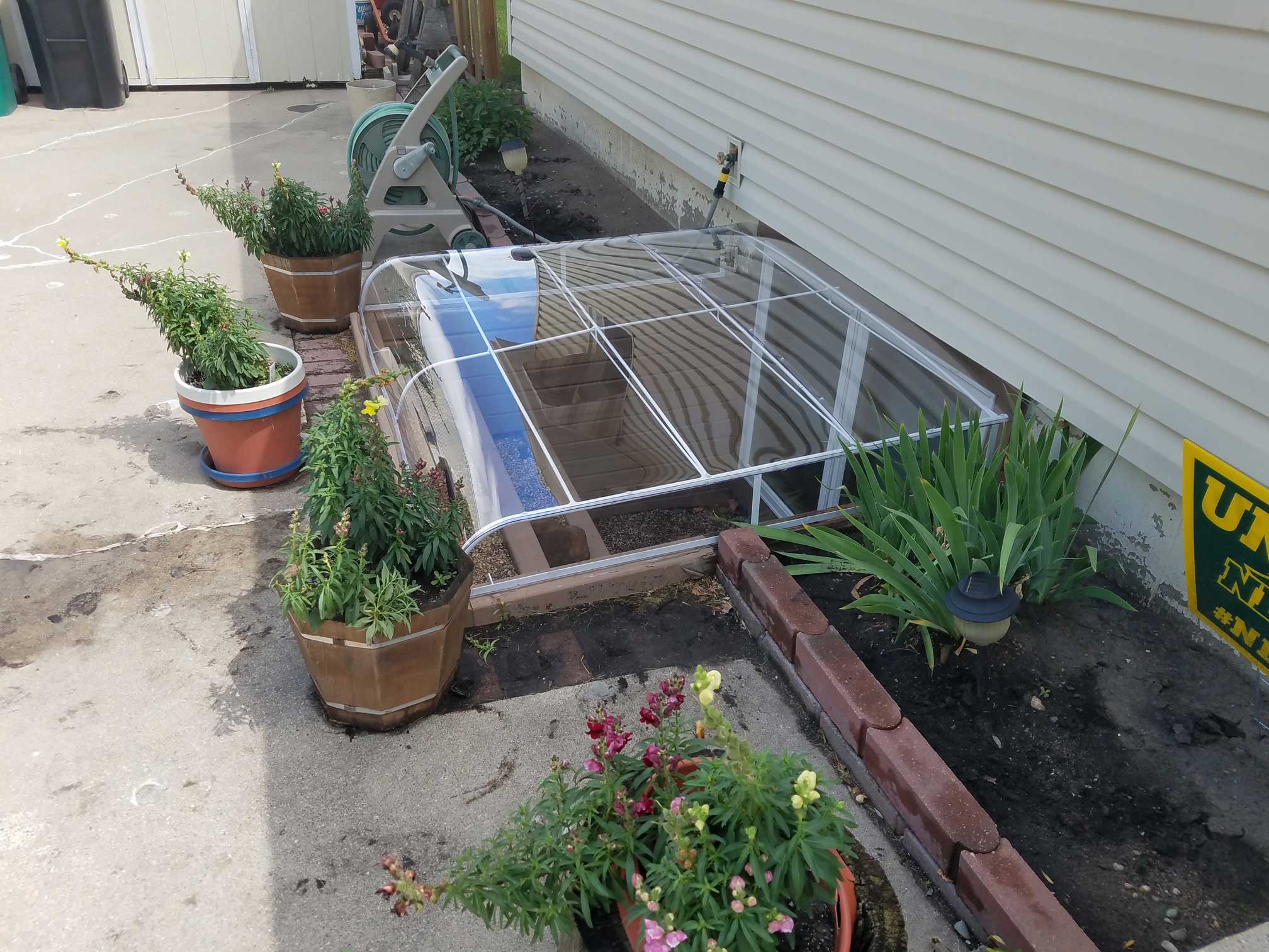 Small cold frame garden with potted plants