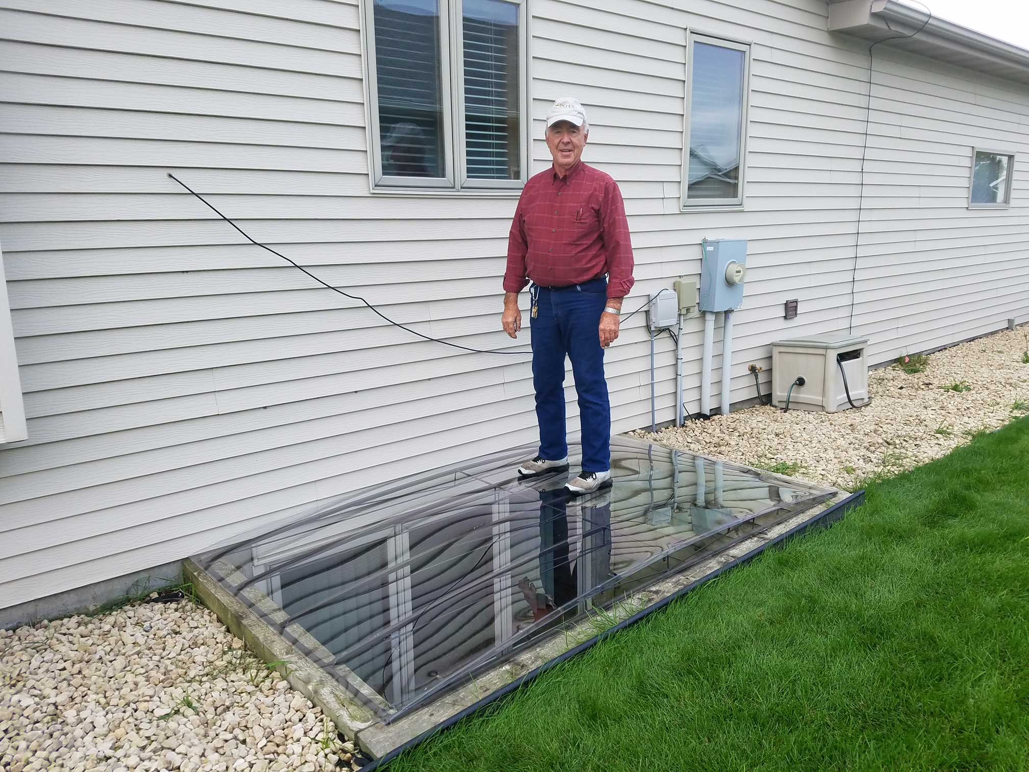 Man standing on glass-covered basement window well