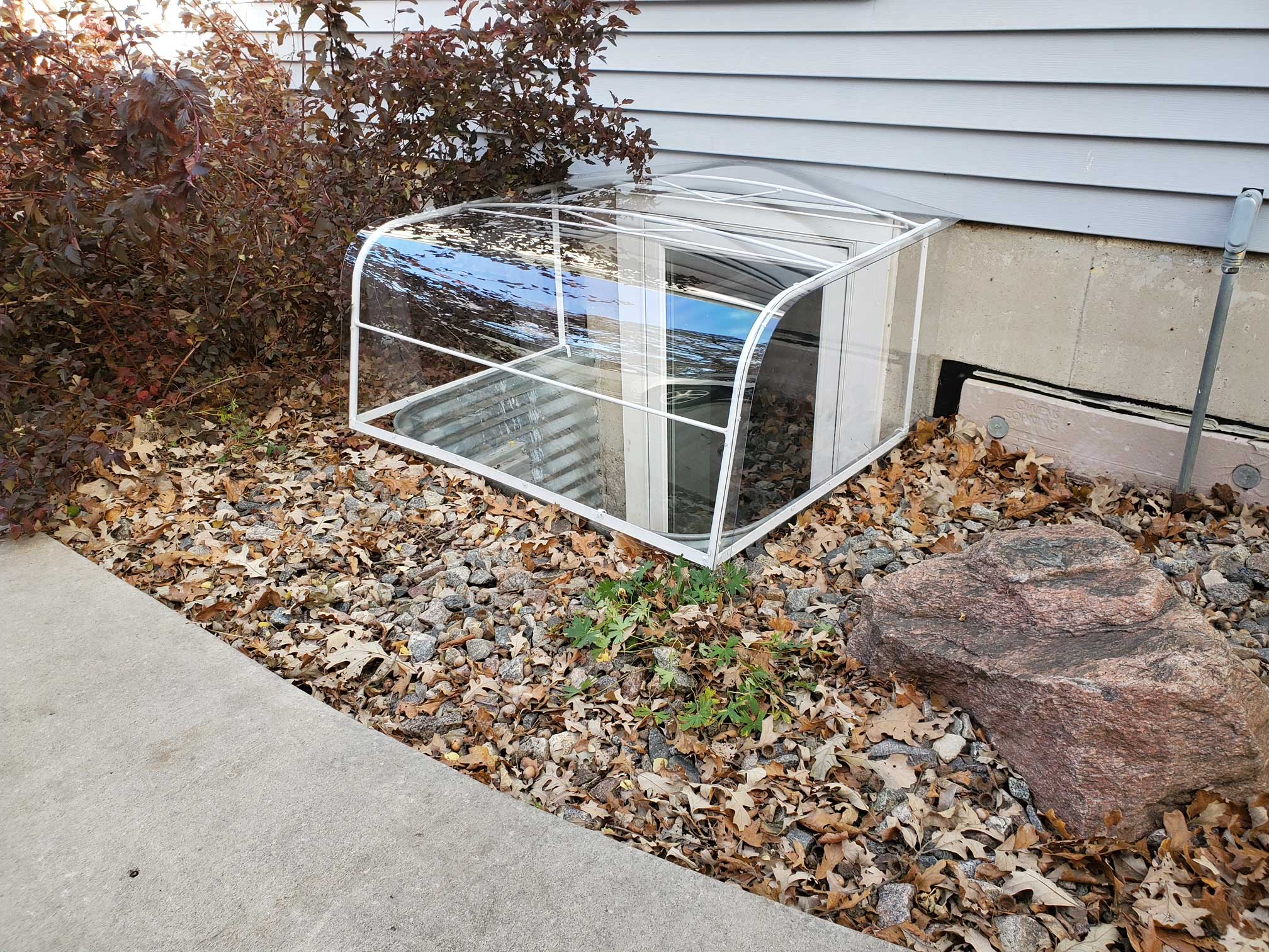 Clear window well cover beside house foundation