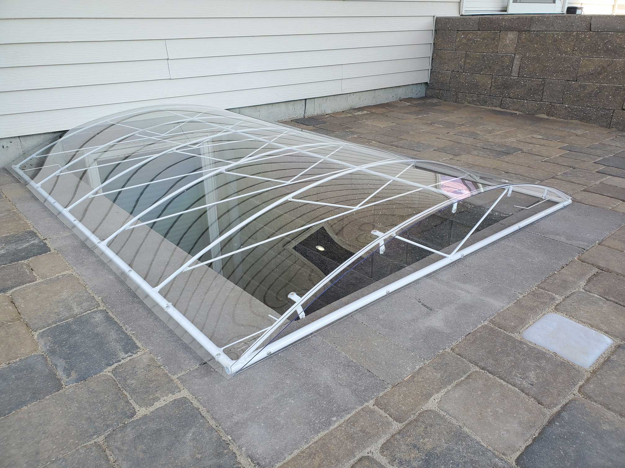 Curved basement window well cover over pavers