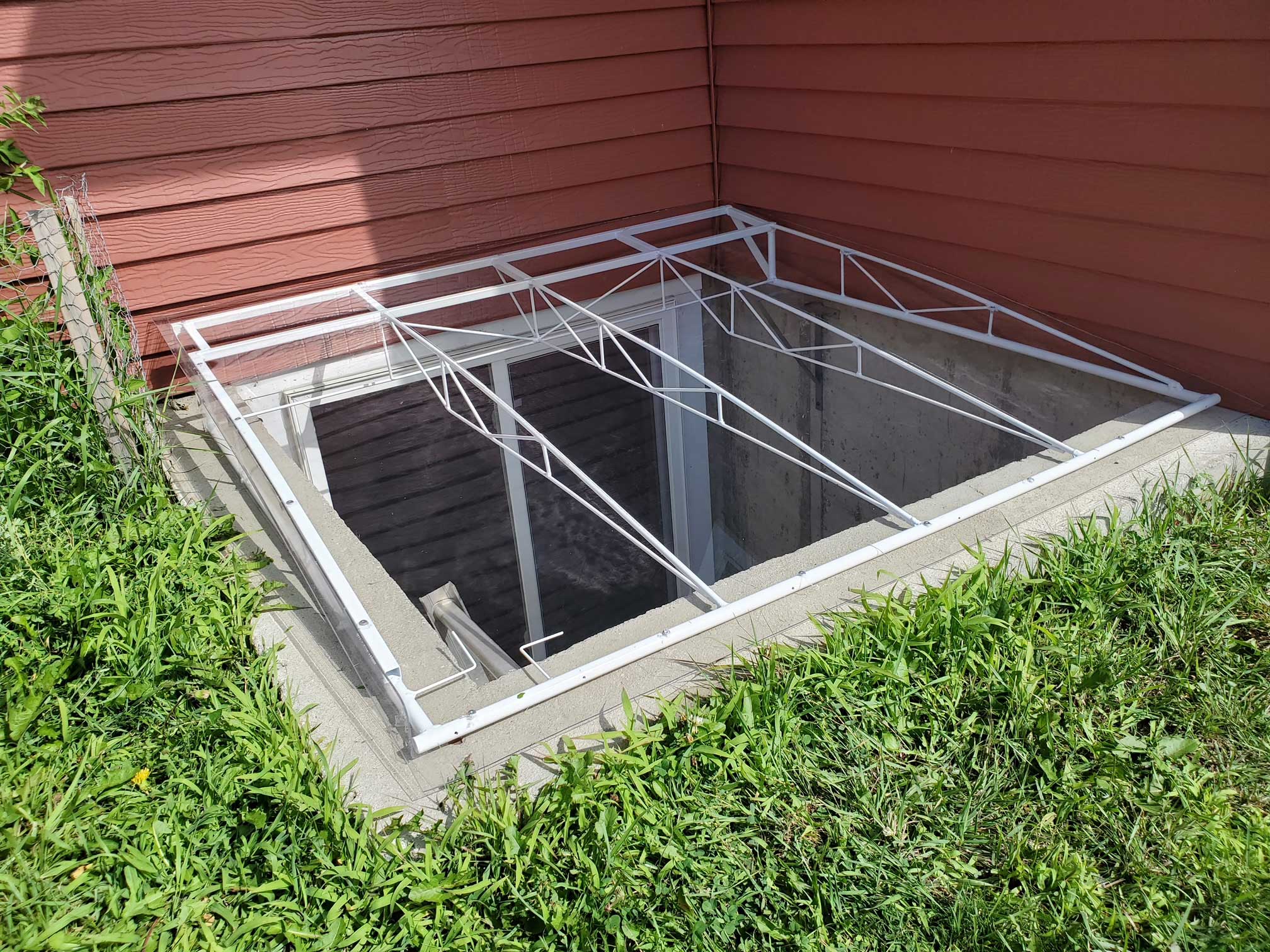 Basement window well with metal security grate