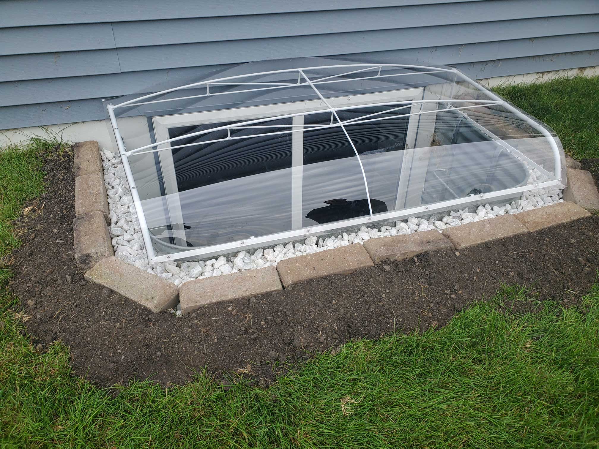 Basement window well with clear domed cover