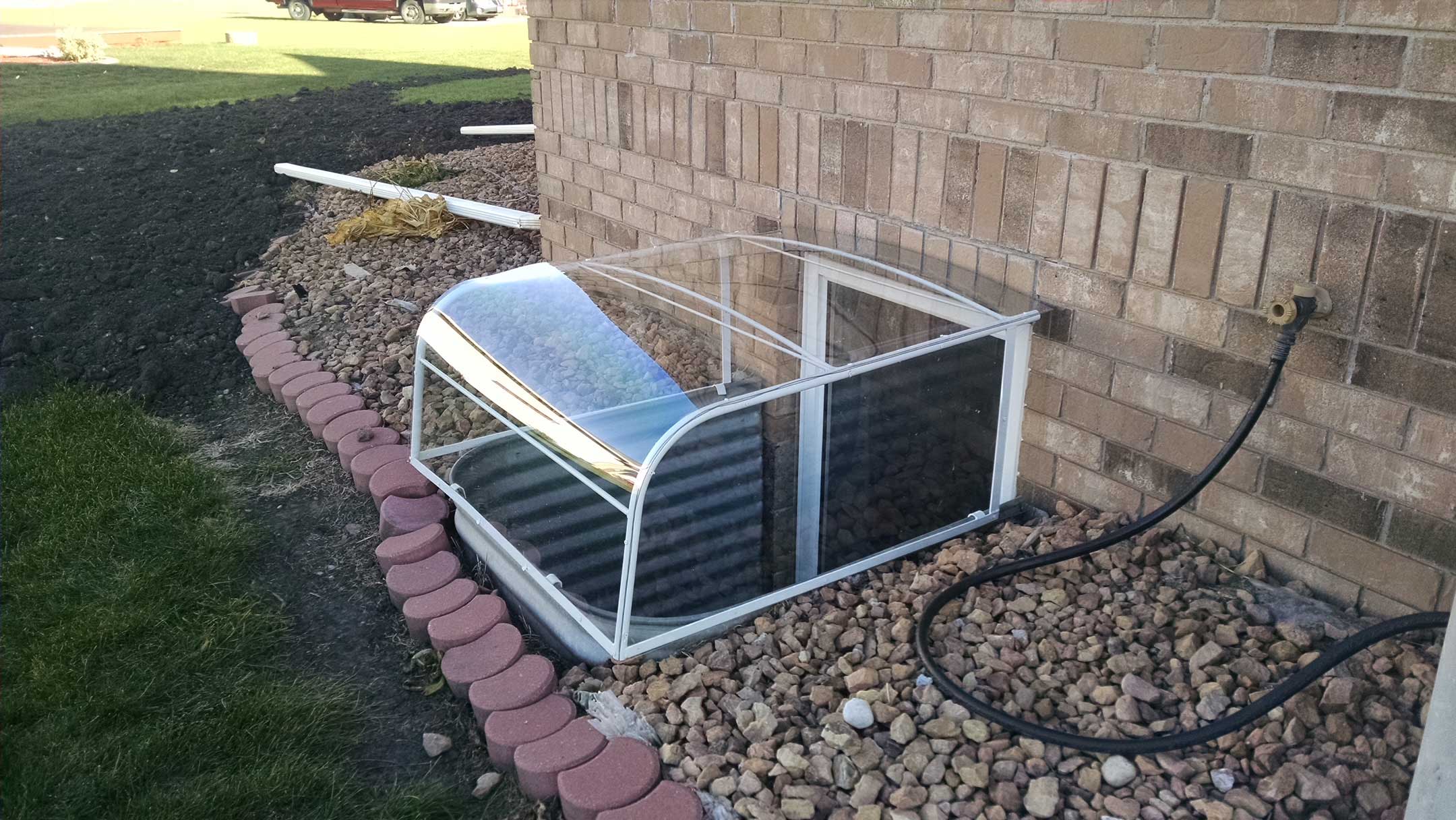 Clear curved window well cover over basement window