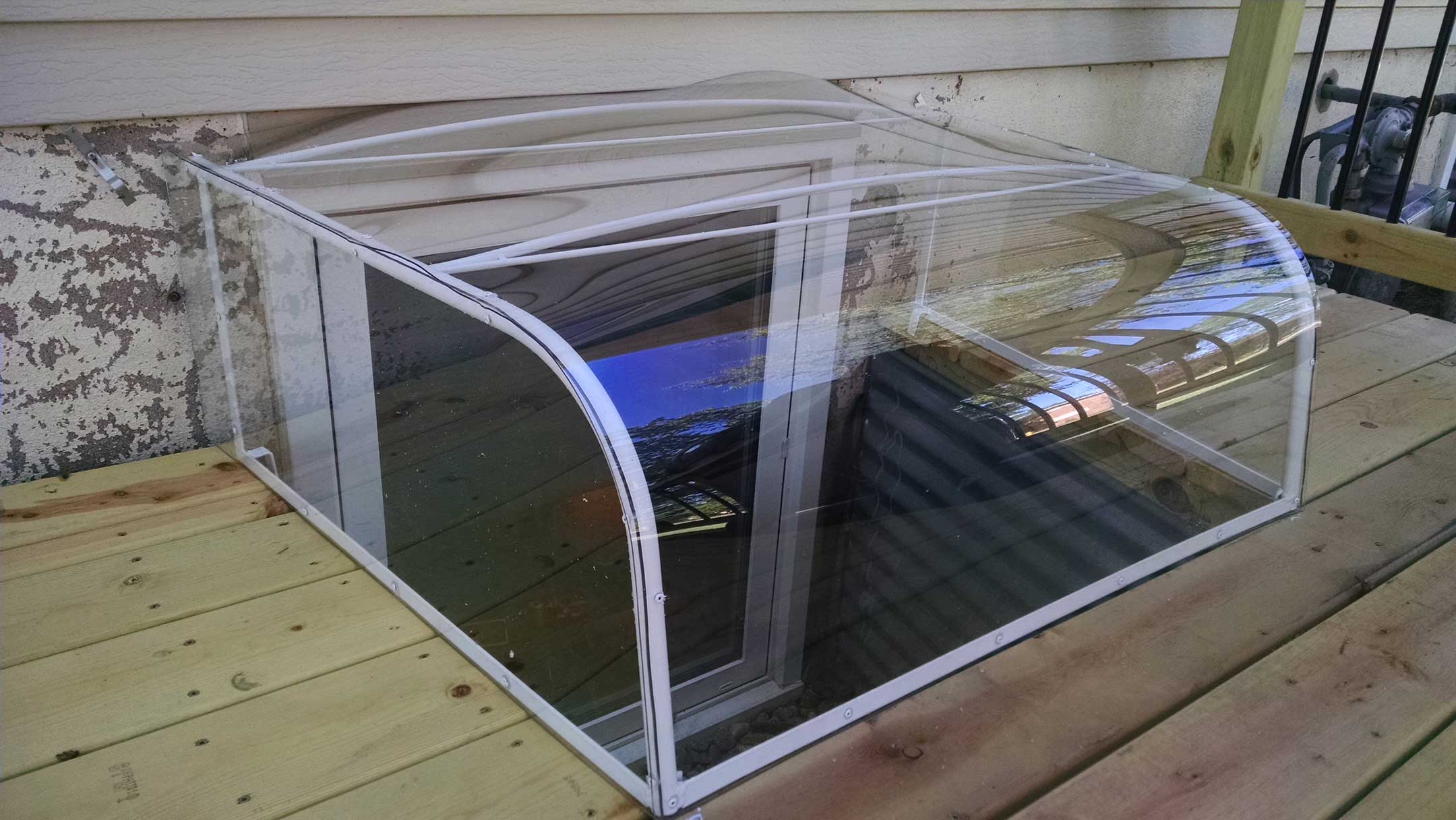 Clear curved window well cover over basement window