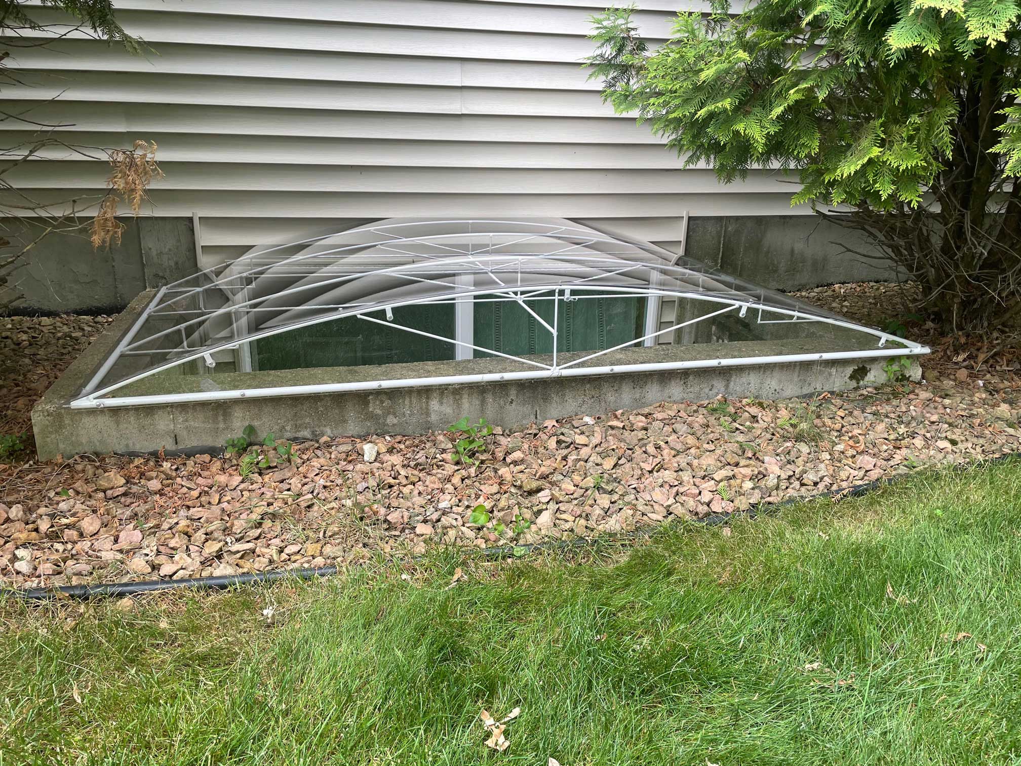 Plastic dome window well cover by house
