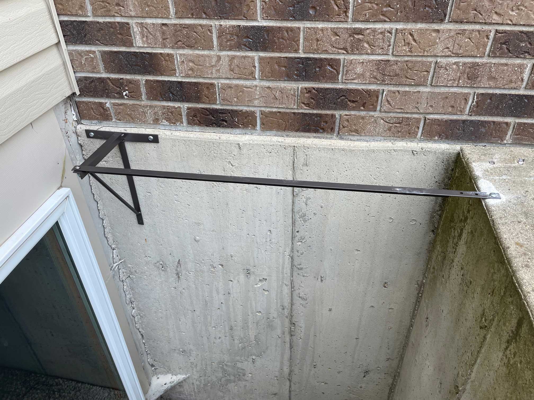 Basement window well with metal support bar