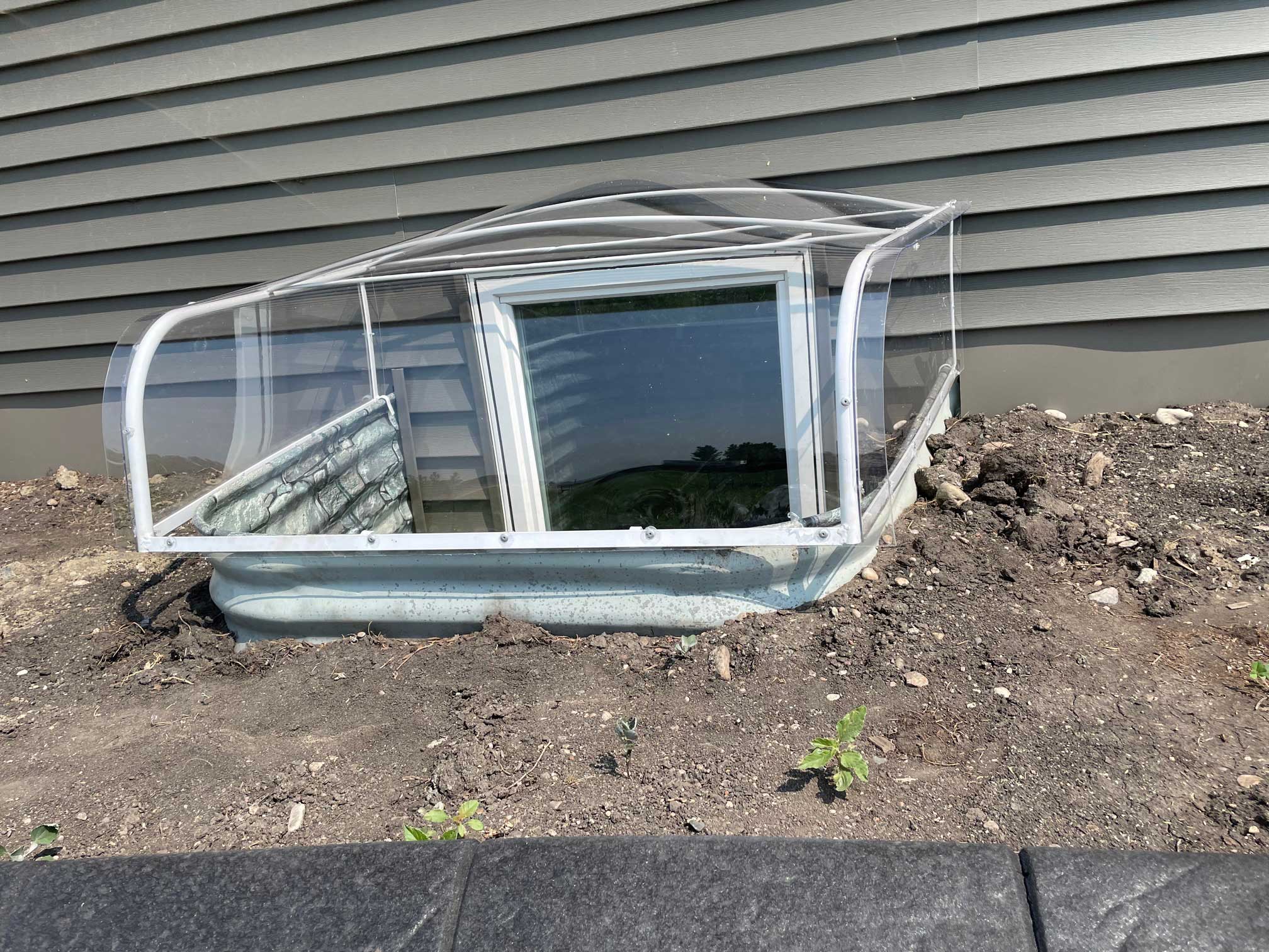 Basement window with clear plastic well cover