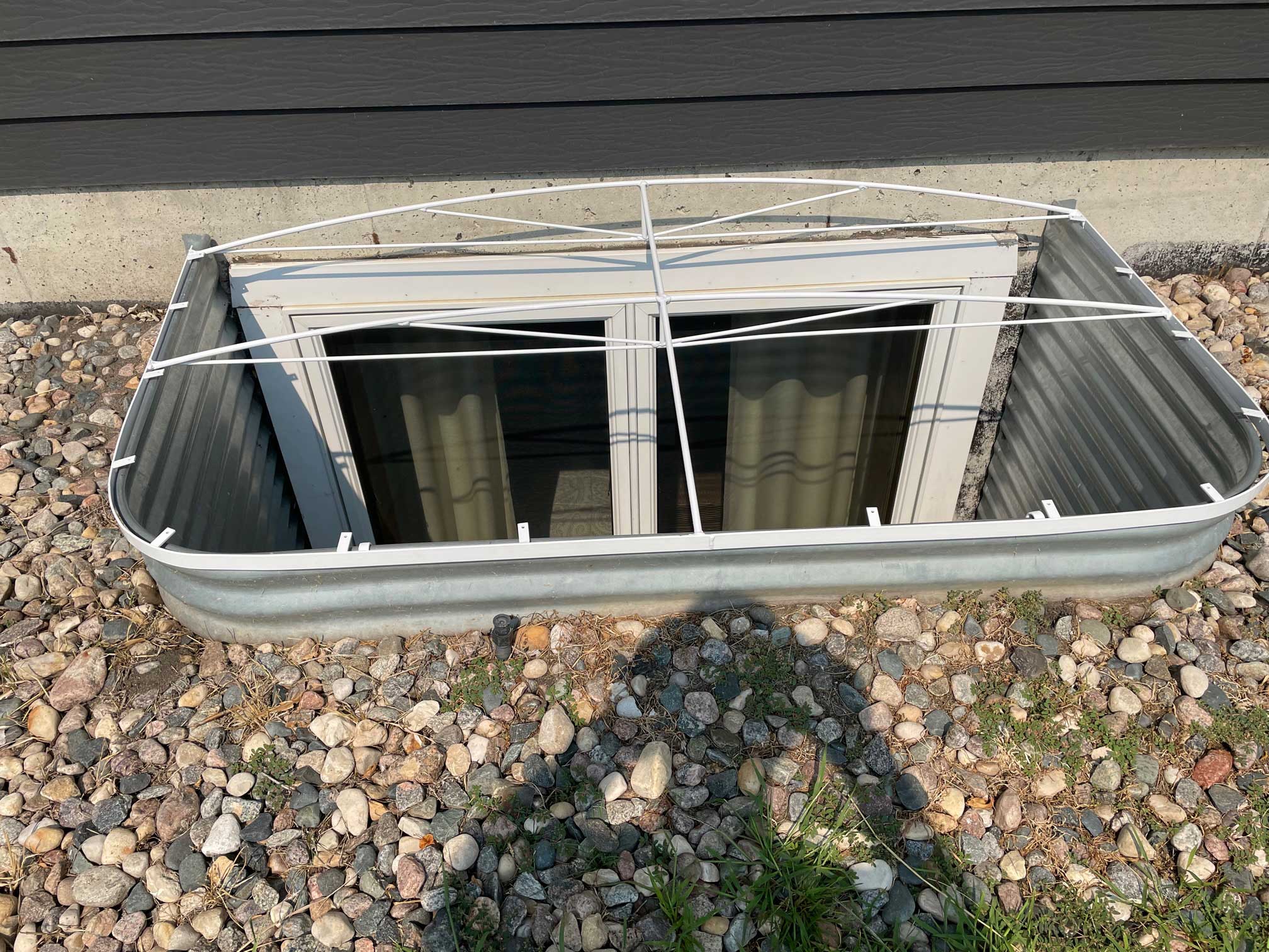 Basement window well with metal protective grate