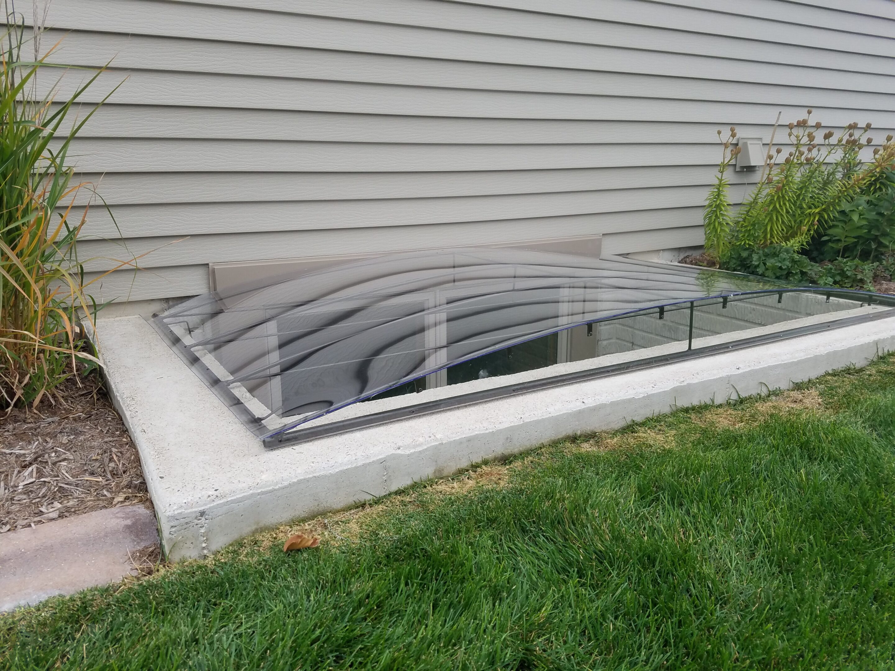 Basement window well with clear plastic cover