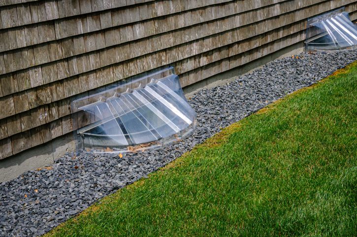 Plastic basement window well covers help to keep leaves, snow, rain and debris from the celler wells on a Cape Cod home