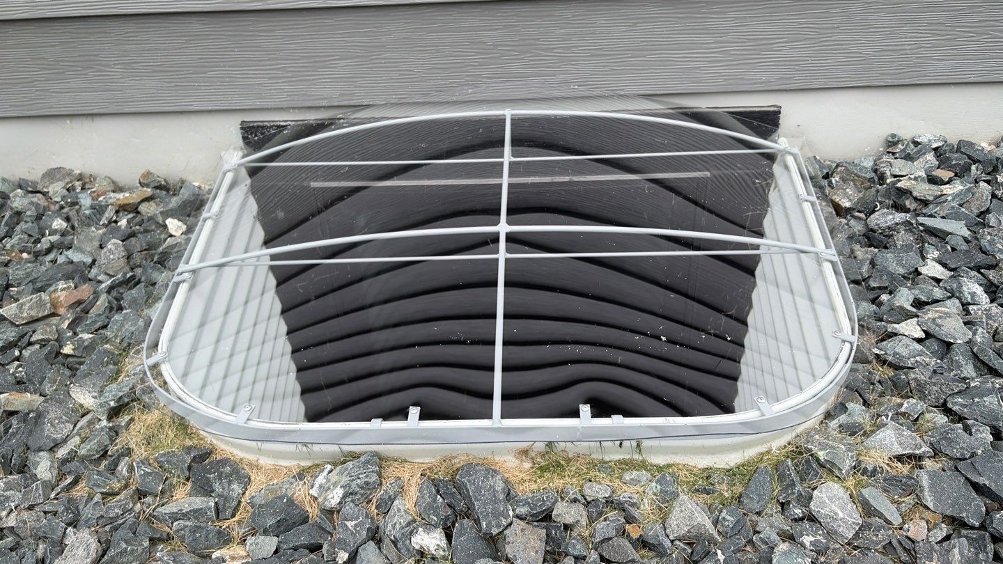 Basement window well covered by metal safety grate
