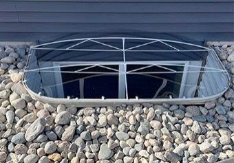 Basement window with protective cover and stones.